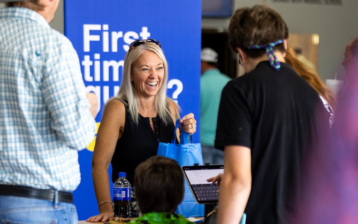 A greeter welcoming guests at the First Time Guest table